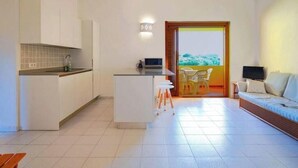 Una cucina moderna con mobili bianchi, un'isola centrale e un'area pranzo con tavolo e sedie.