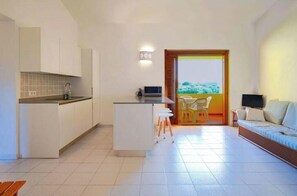 A modern kitchen with white cabinets, a central island, and a dining area with a table and chairs. - Cozy apartment with 2 bedrooms, 2 bathrooms and terrace (Salina Bamba)