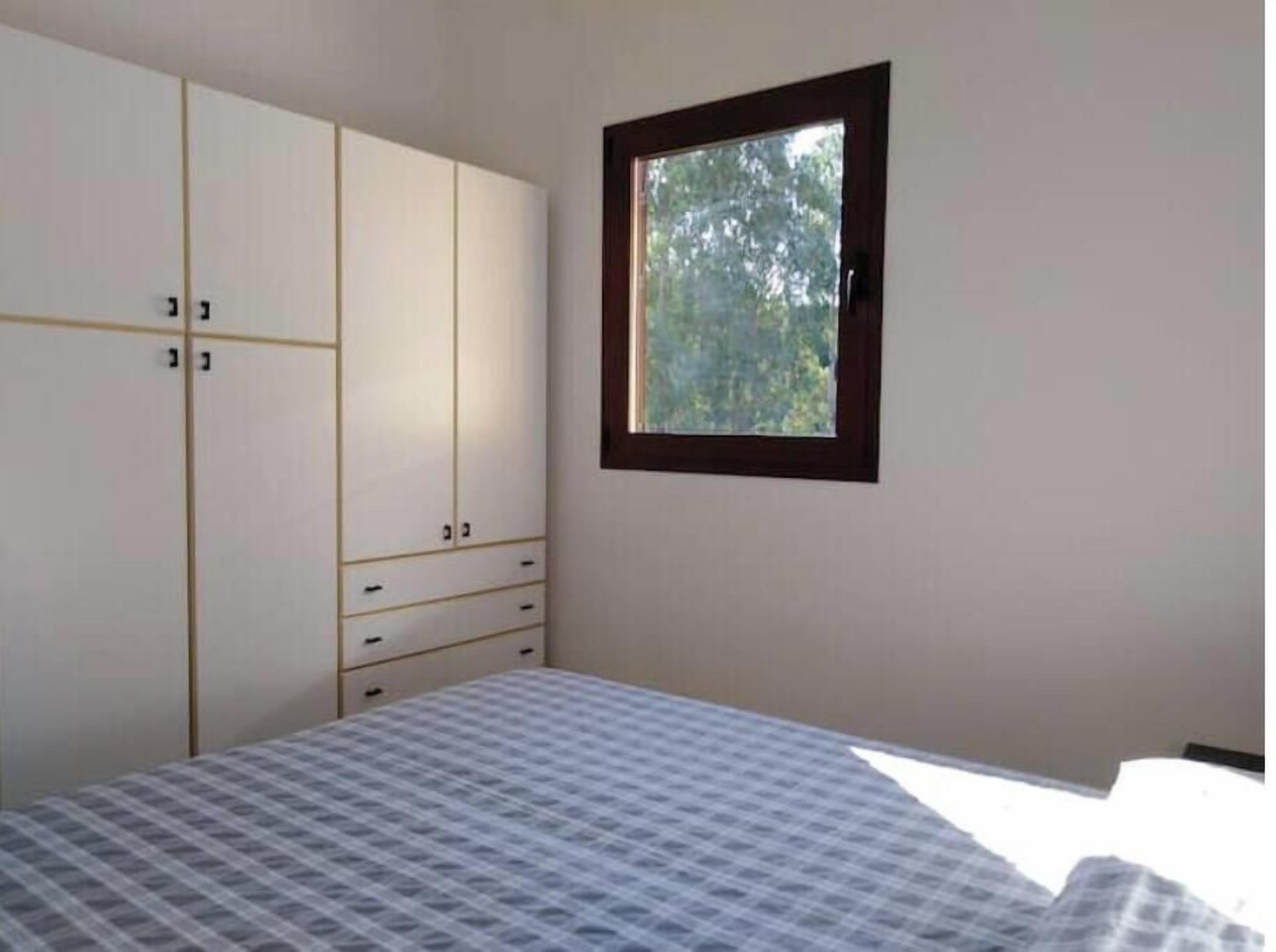 Un dormitorio con cama, armario y ventana.