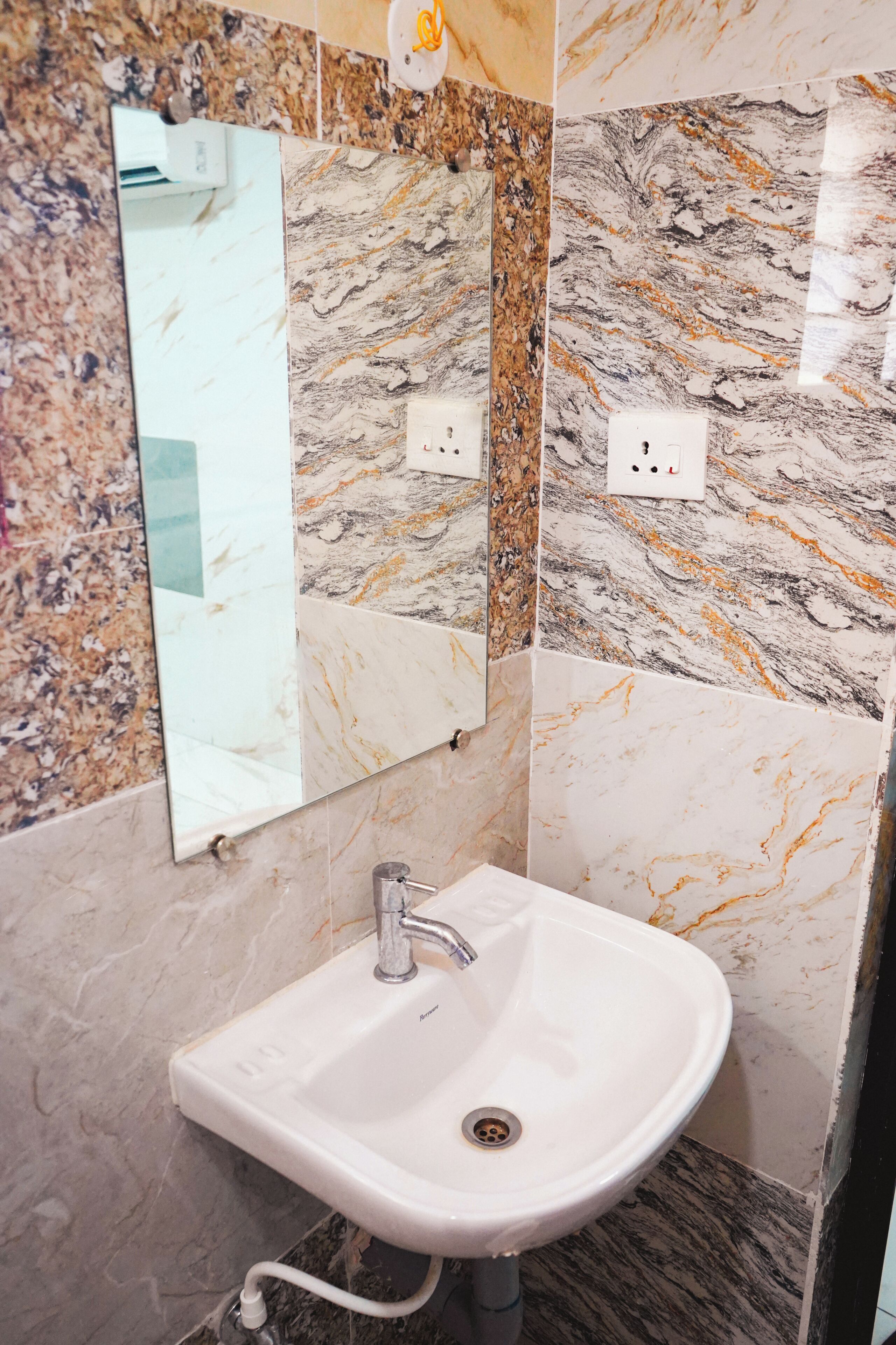 A bathroom with a white sink, a mirror, and marble-patterned walls.