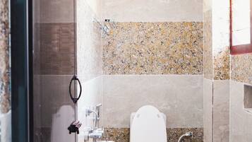 Baño con ducha, inodoro, lavamanos y dos cubetas amarillas.