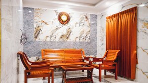A room with a marble wall, a wooden bench, and a curtain. - SUMI WHITE HOUSE (Thanjavur)