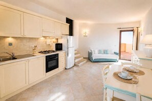 A modern kitchen with a dining area, a refrigerator, and a sofa. - Porto San Paolo - Sea View House with Garden (Porto San Paolo)