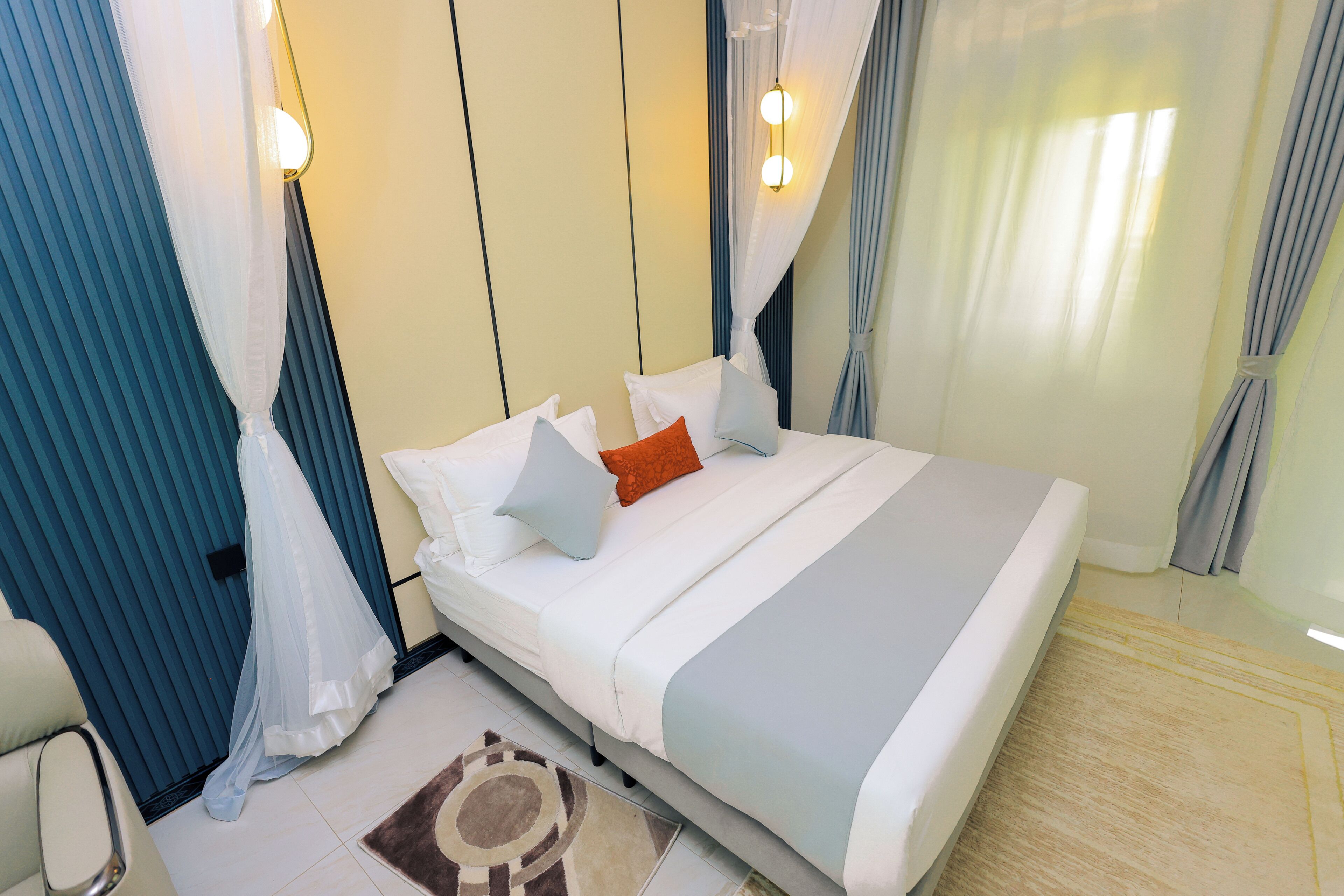 Una habitación de hotel con cama, cortinas, una silla y una alfombra.