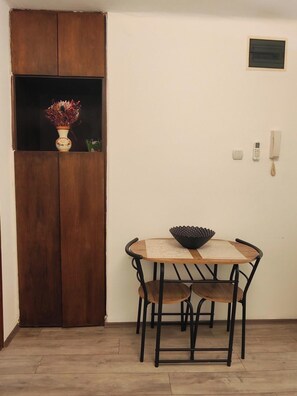 A room with a wooden cabinet, a small table with a bowl, two chairs, a wall-mounted phone, and a light switch. - The Best offer! 2-bedroom apartment in Vracar with AC for relaxing stays (Beograd)