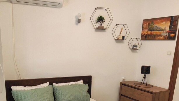 A bedroom with a bed, a dresser, an air conditioner, and wall decorations. - The Best offer! 2-bedroom apartment in Vracar with AC for relaxing stays (Beograd)