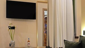 A modern living room with a flat-screen TV, a sofa, a round coffee table, and a mirror. - Apon City Residence (Chania)