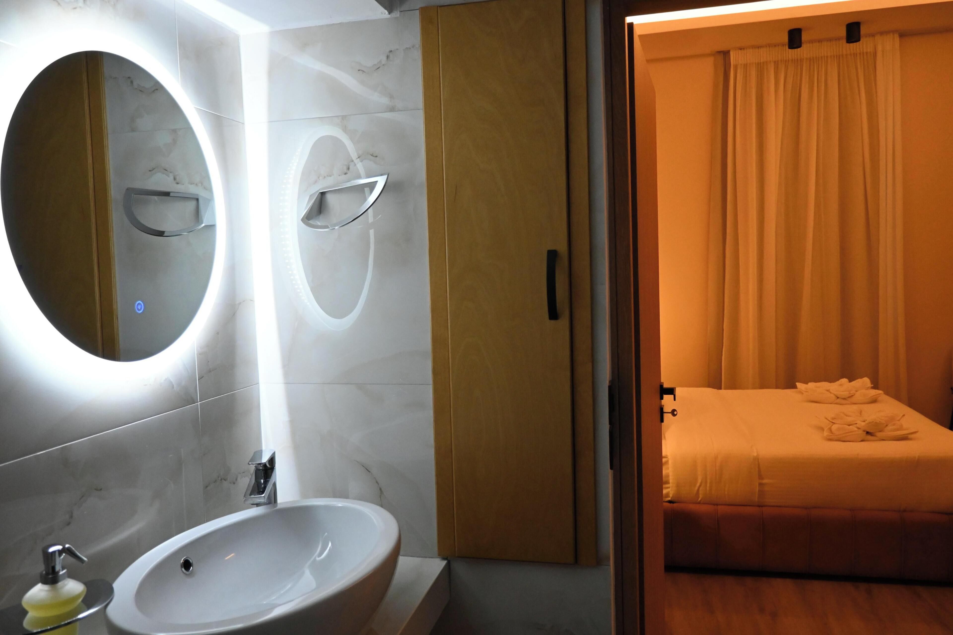 Une salle de bain moderne avec un grand miroir rond, un lavabo et une douche.