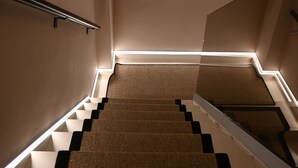 A staircase with a handrail, a window with blinds, and a small statue on a shelf. - Apon City Residence (Chania)