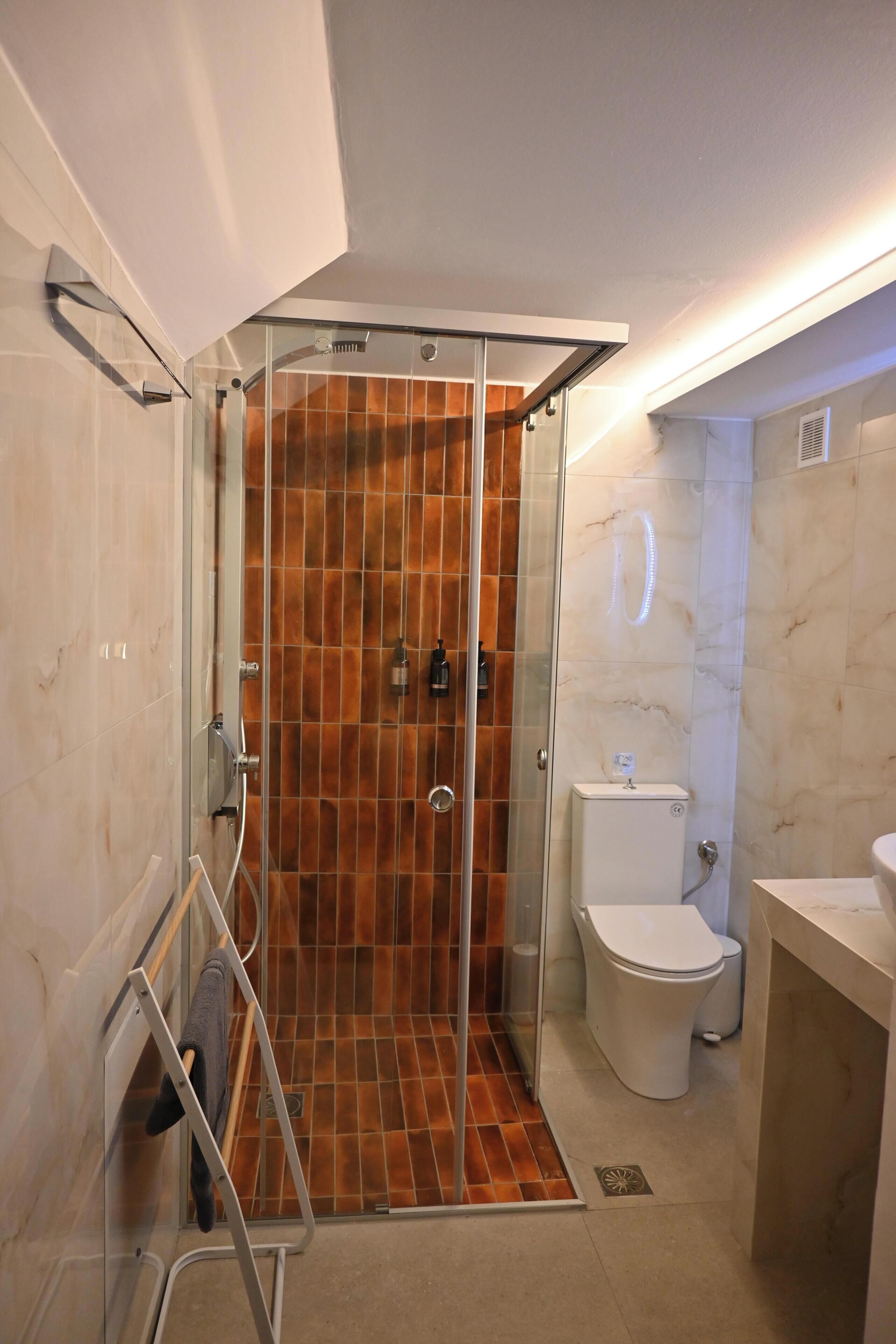 Un baño con ducha acristalada, inodoro y lavamanos.