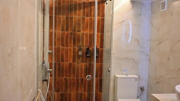 Un baño con ducha acristalada, inodoro y lavamanos.