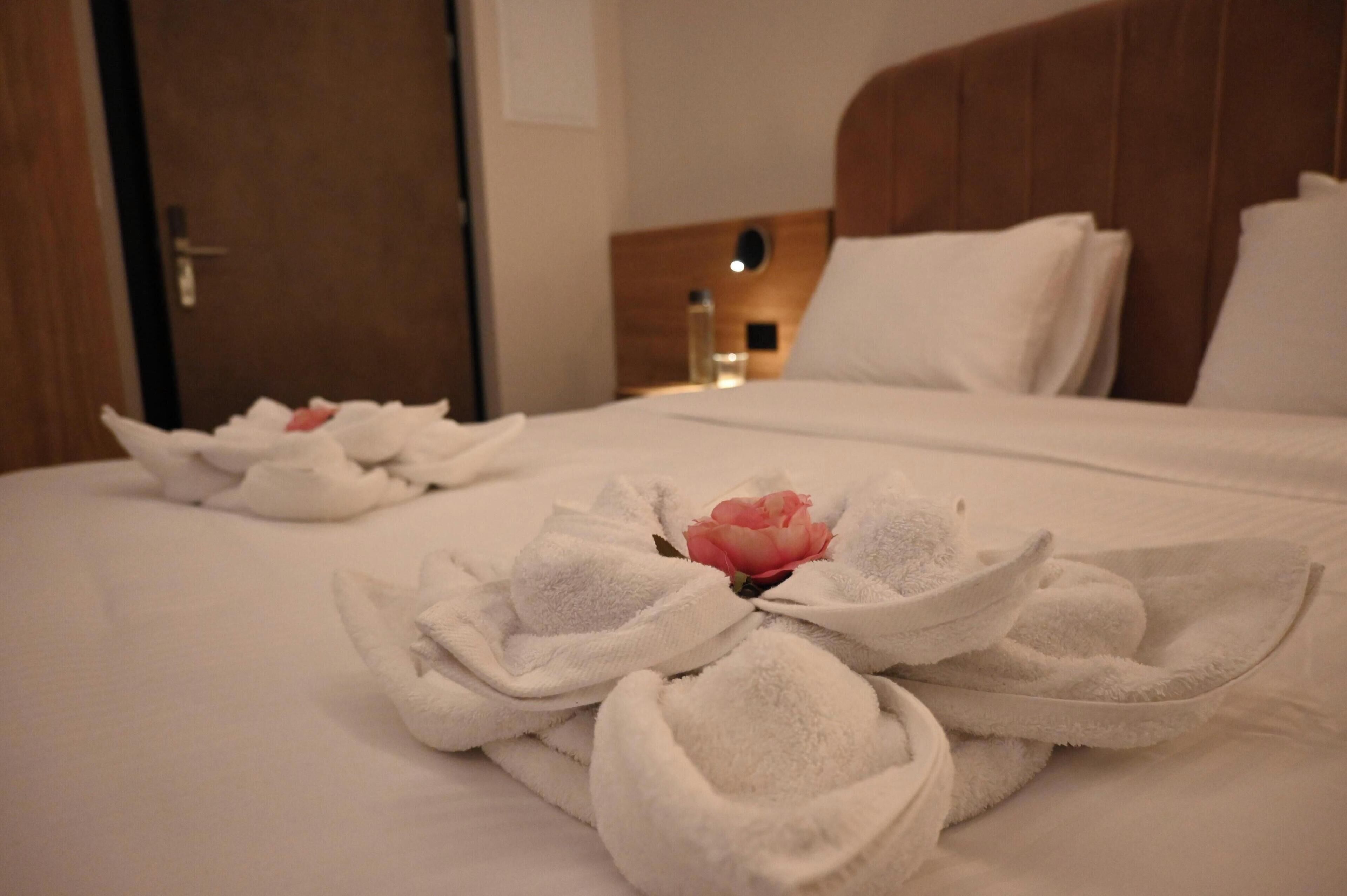 A hotel room with a neatly made bed, a wooden headboard, and a nightstand with a bottle.