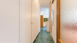 A narrow hallway with white walls, a green patterned floor, and a wooden door frame. - Anna Flat (Lido di Jesolo)