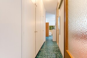 A narrow hallway with white walls, a green patterned floor, and a wooden door frame. - Anna Flat (Lido di Jesolo)