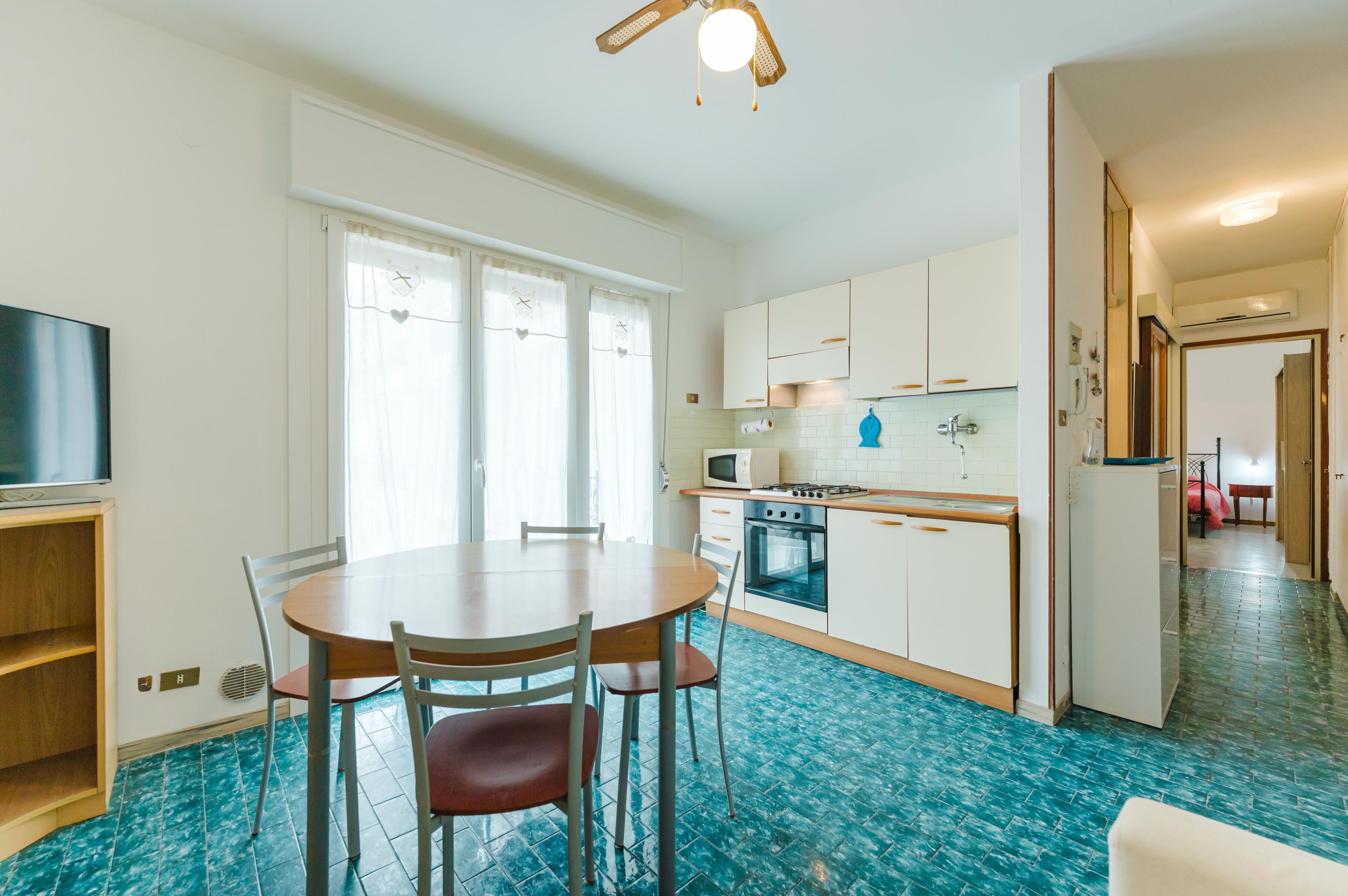 A kitchen with white cabinets, a microwave, a stove, and a dining table with chairs.
