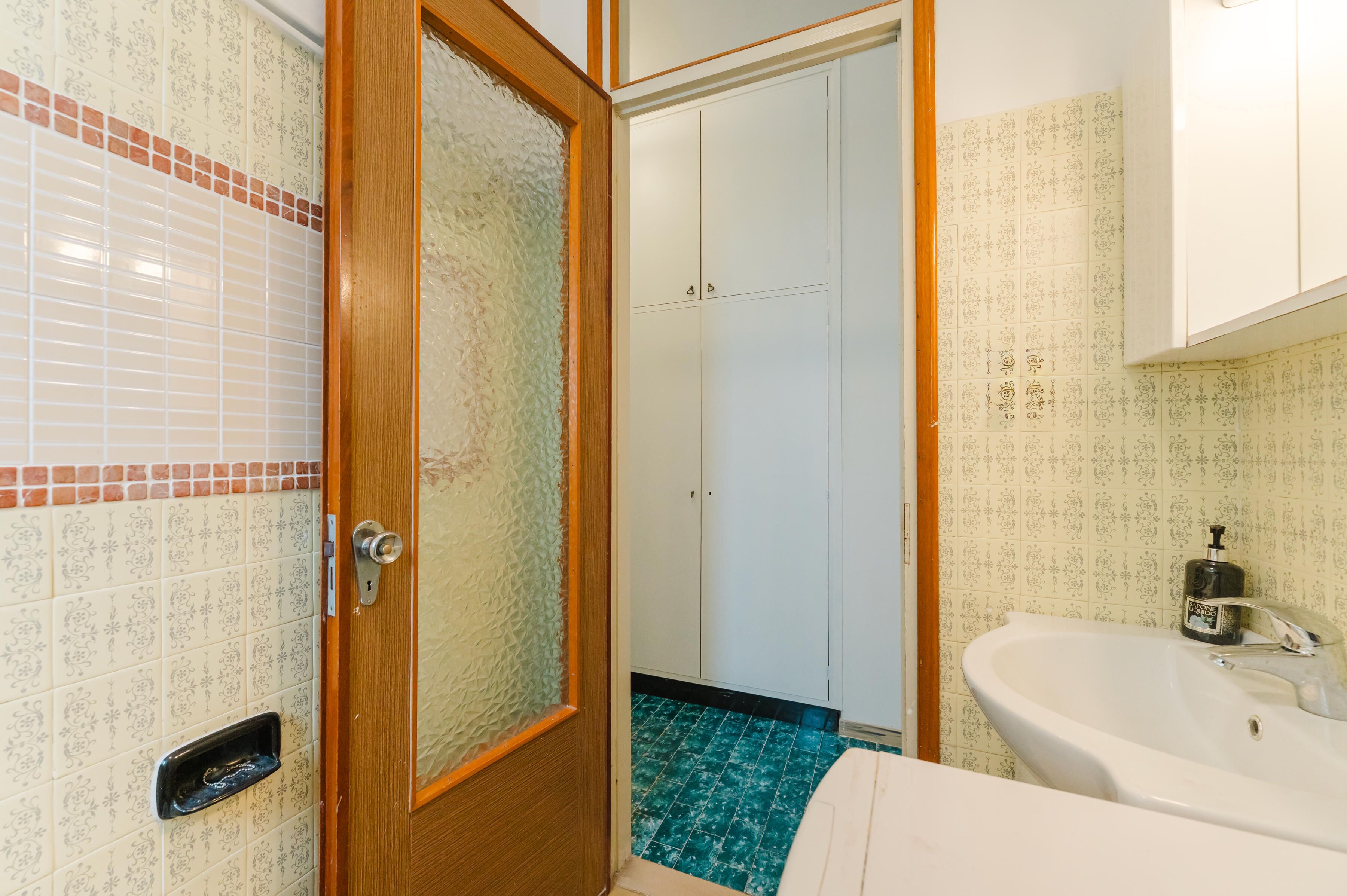 A bathroom with a white sink, a wooden door, and patterned tiles.