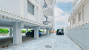 A covered parking area with multiple cars parked under a building. - Anna Flat (Lido di Jesolo)