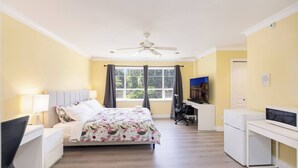 A bedroom with a bed, desk, chair, and a ceiling fan. - Room-cozy & Huge Primary Suite Near UBC (Vancouver)