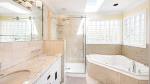 A modern bathroom with a glass-enclosed shower, a large bathtub, and a vanity with a sink. - Room-cozy & Huge Primary Suite Near UBC (Vancouver)