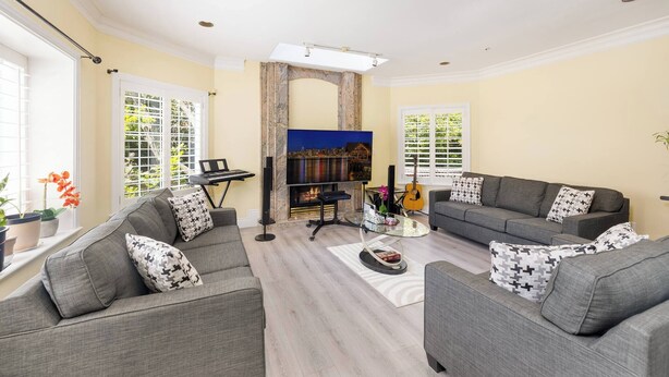 A living room with a fireplace, a sofa set, a coffee table, and a guitar. - Room-cozy & Huge Primary Suite Near UBC (Vancouver)