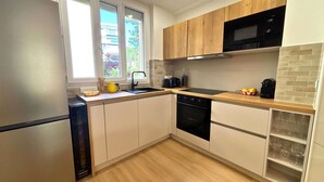 Een moderne keuken met een koelkast, fornuis, magnetron en houten kastjes.