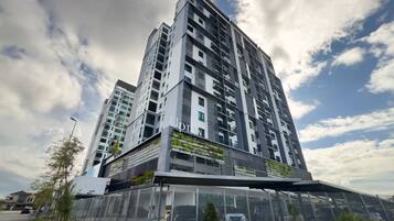 A high-rise building with multiple balconies, a modern architectural design, and a clear sky with clouds.