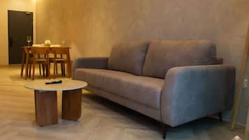 Uma sala de estar moderna com um sofá, uma mesa de jantar com cadeiras e uma pequena mesa de centro.
