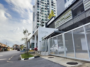 A modern building with a covered outdoor area, a car parked inside, and a clear sky.