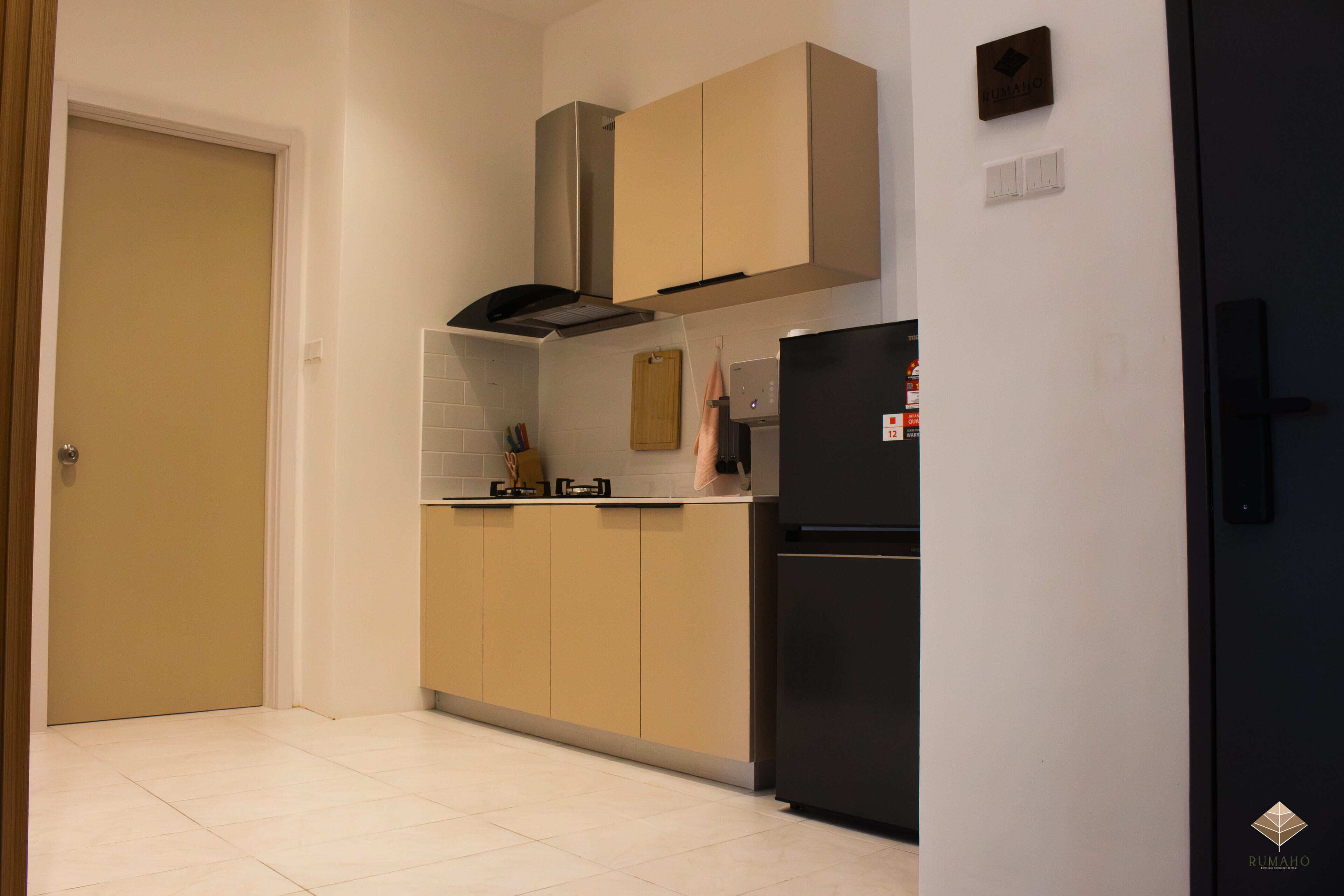 Una cocina con armarios color beige, un refrigerador negro y una campana extractora de acero inoxidable.