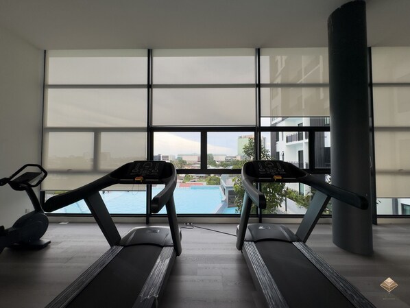 A gym with two treadmills, large windows, and a view of a swimming pool.