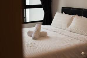 A neatly made bed with white linens and pillows, a window with curtains, and a dark headboard.
