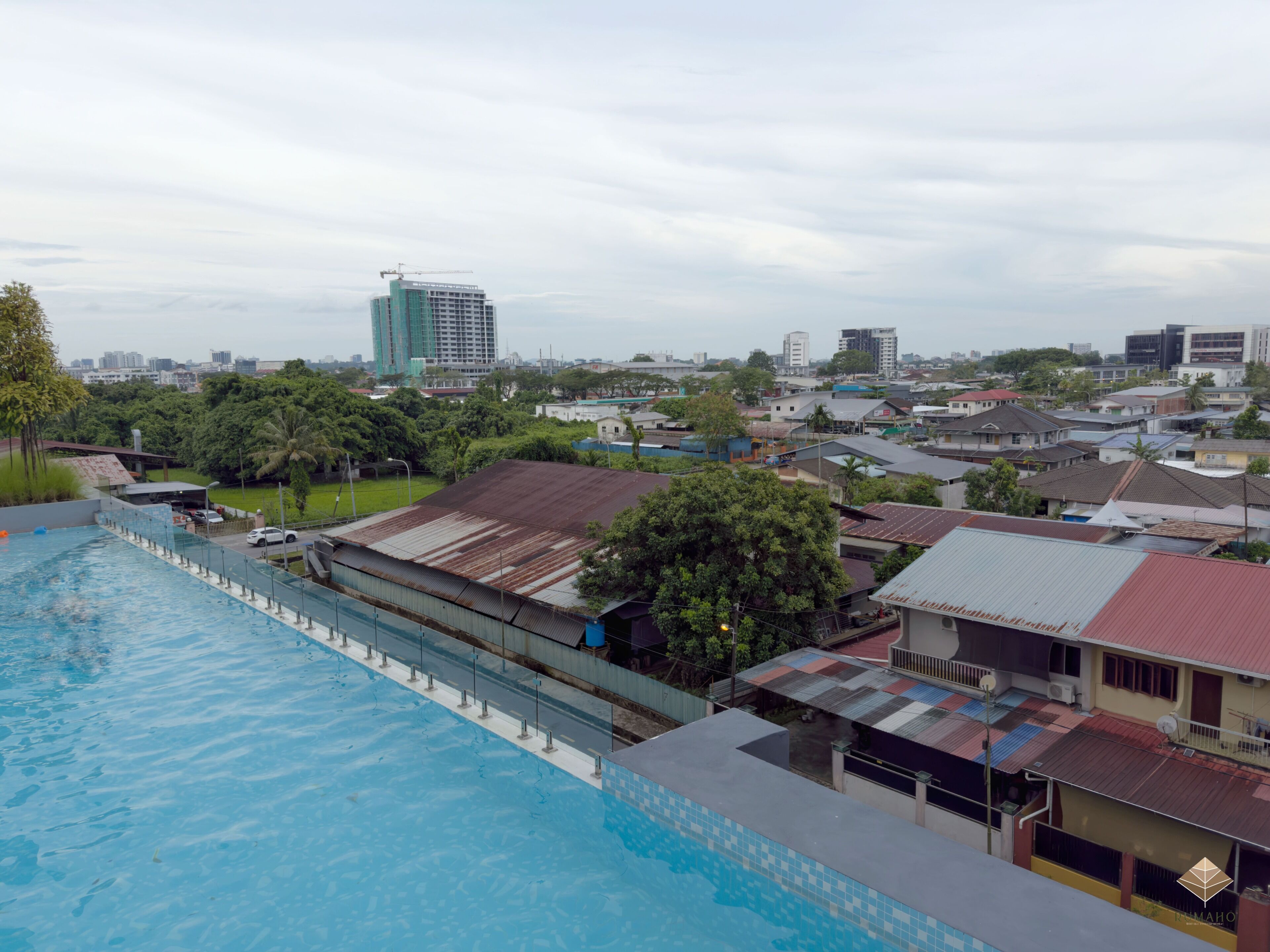 Zona residencial con piscina, casas y un edificio grande en construcción.