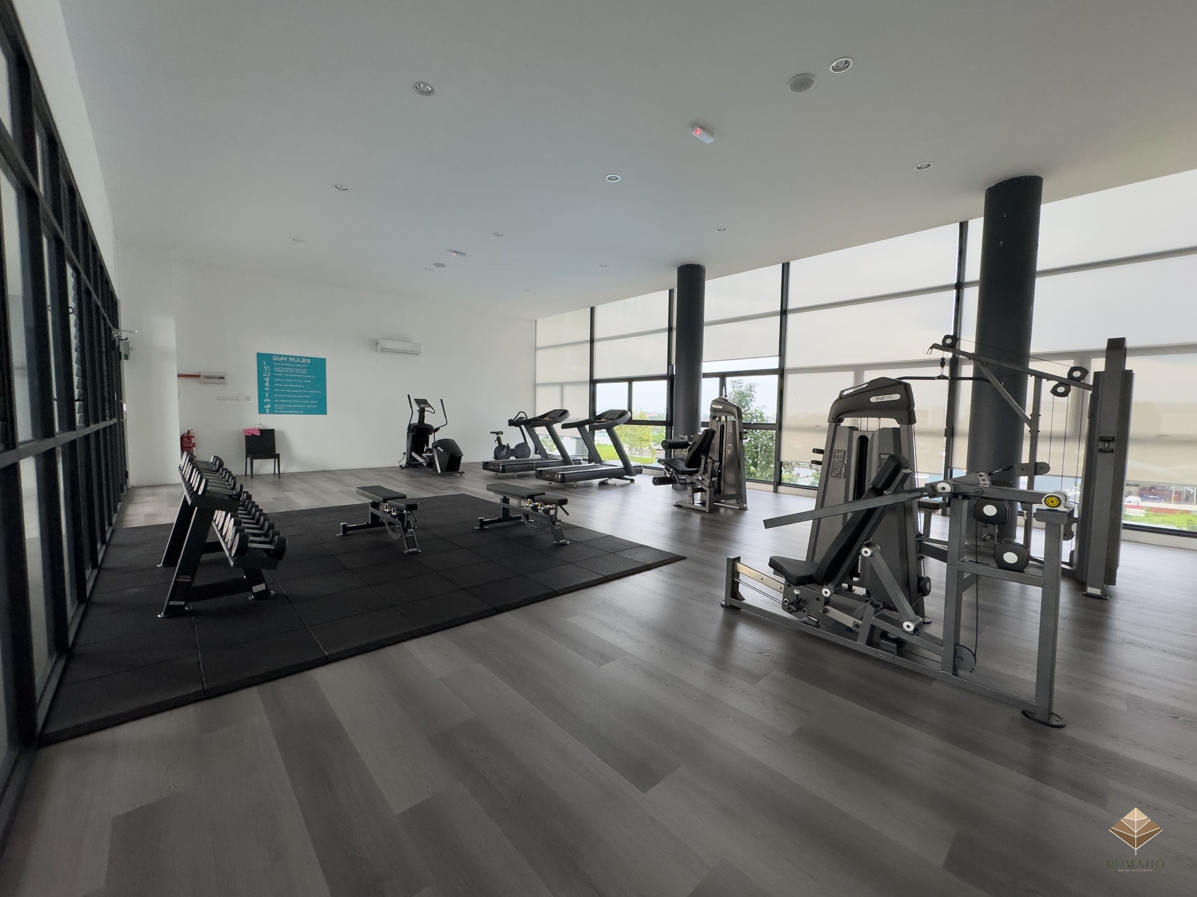 Een moderne sportschool met cardioapparatuur, gewichten en een groot raam met uitzicht op het buiten.