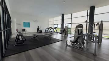 Een moderne sportschool met cardioapparatuur, gewichten en een groot raam met uitzicht op het buiten.