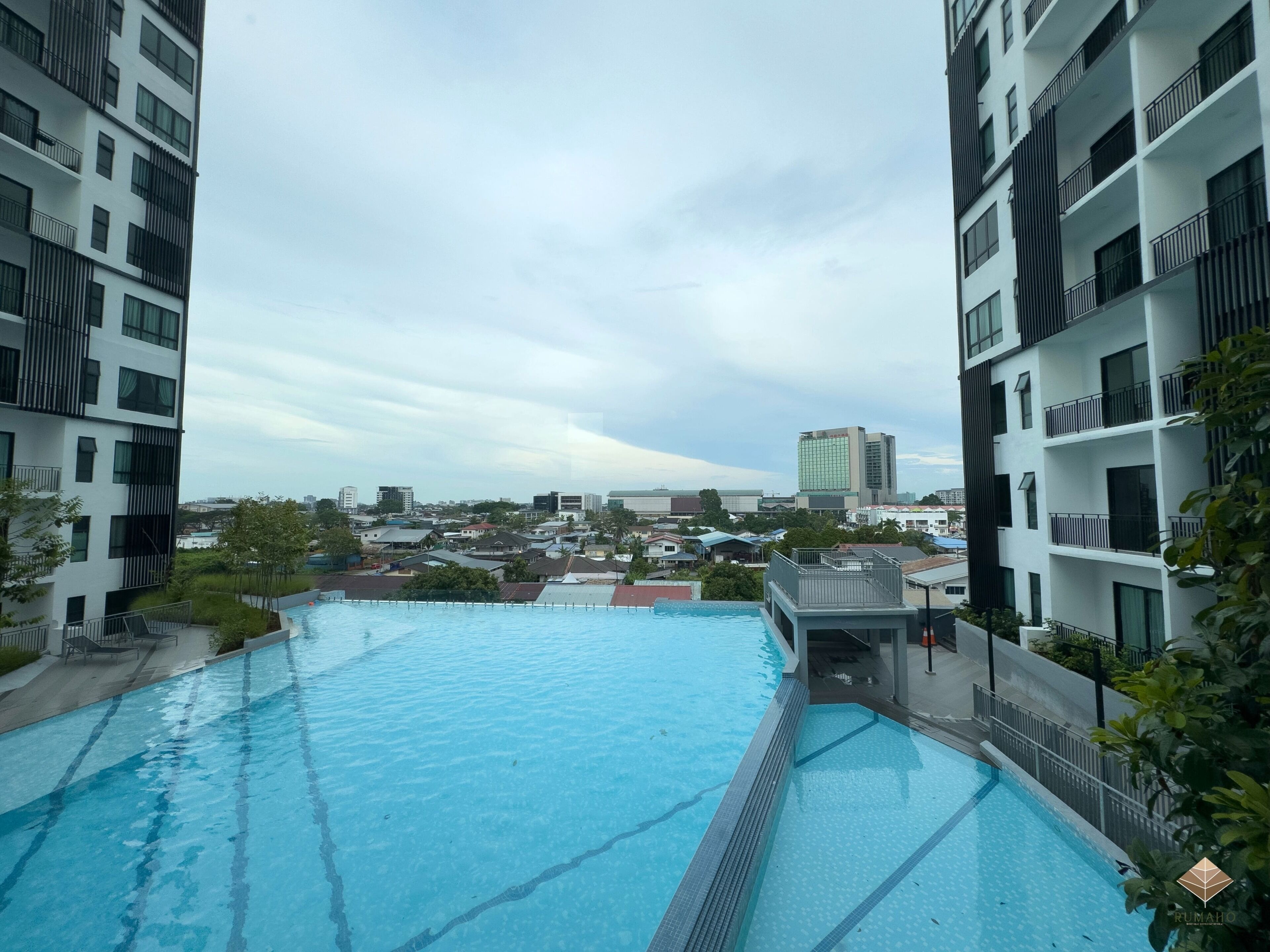 A modern building with a swimming pool, balconies, and a view of the cityscape.