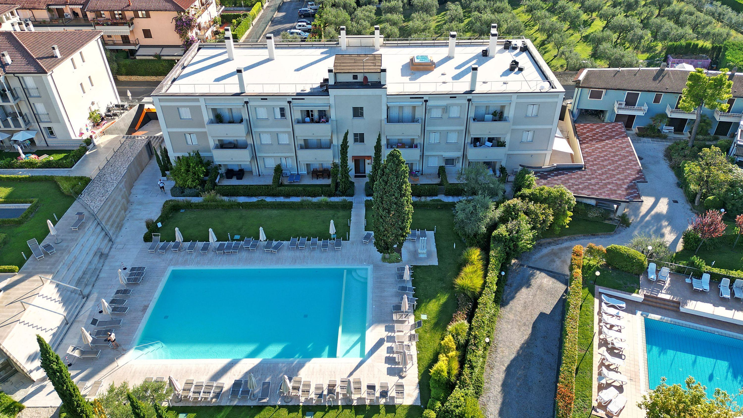 A large building with a swimming pool, multiple balconies, and a well-maintained garden.