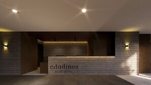 A reception desk with a sign reading 'citadines apart hotel' in a modern lobby with wooden paneling and recessed lighting.