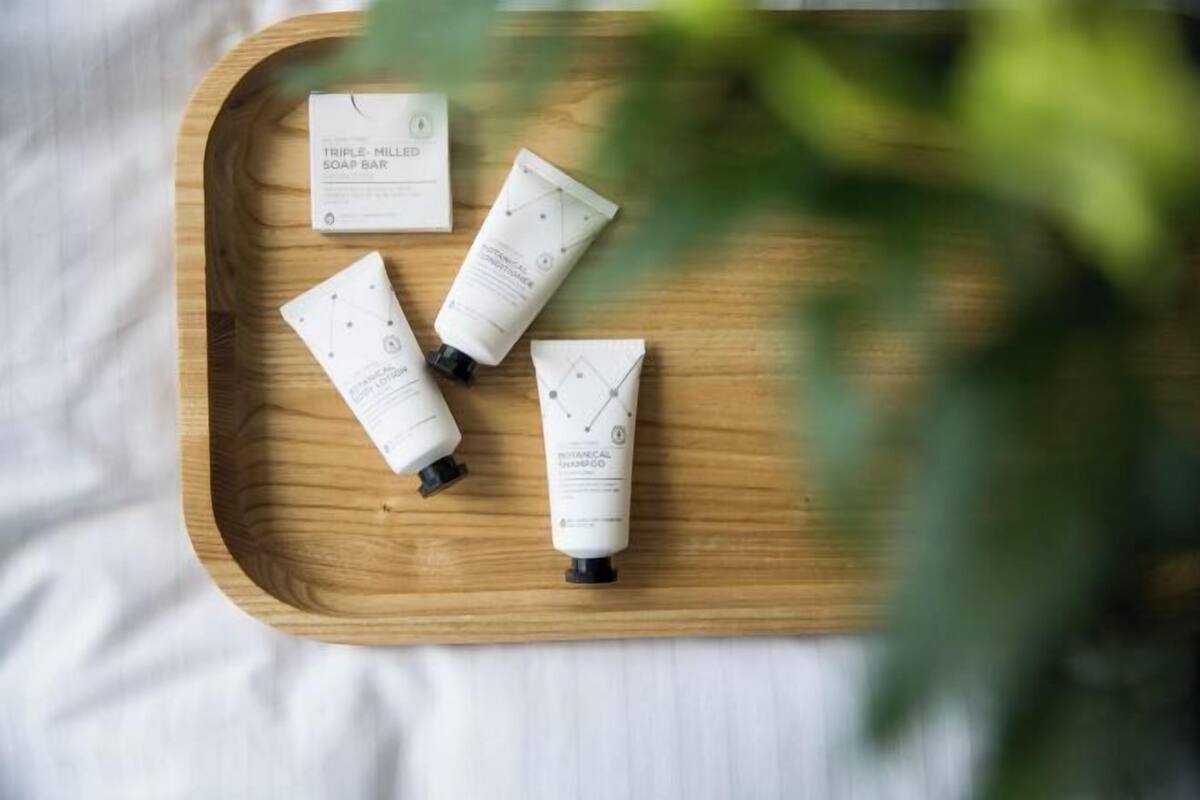 A wooden tray with four skincare products on a white fabric surface.