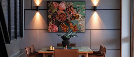 A modern living room with a dining area, featuring a sofa, coffee table, and a painting on the wall.