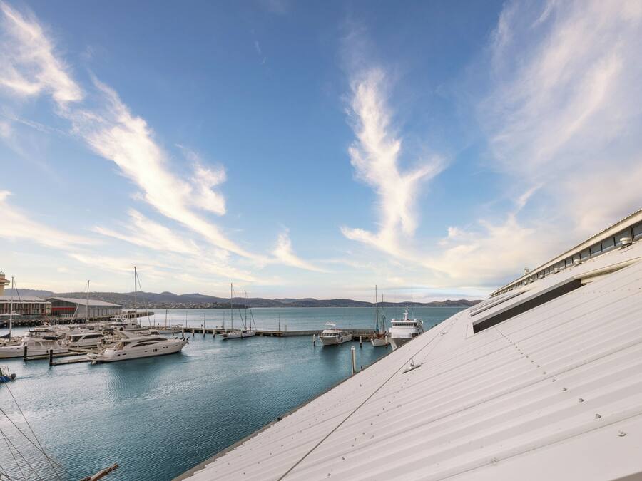 Una marina con barche ormeggiate, un edificio con tetto spiovente e cielo sereno con nuvole.