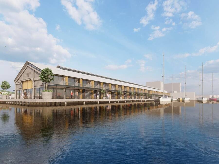Un edificio frente al agua con un techo plano y largo, un corredor cubierto y un área de embarcaderos con barcos.