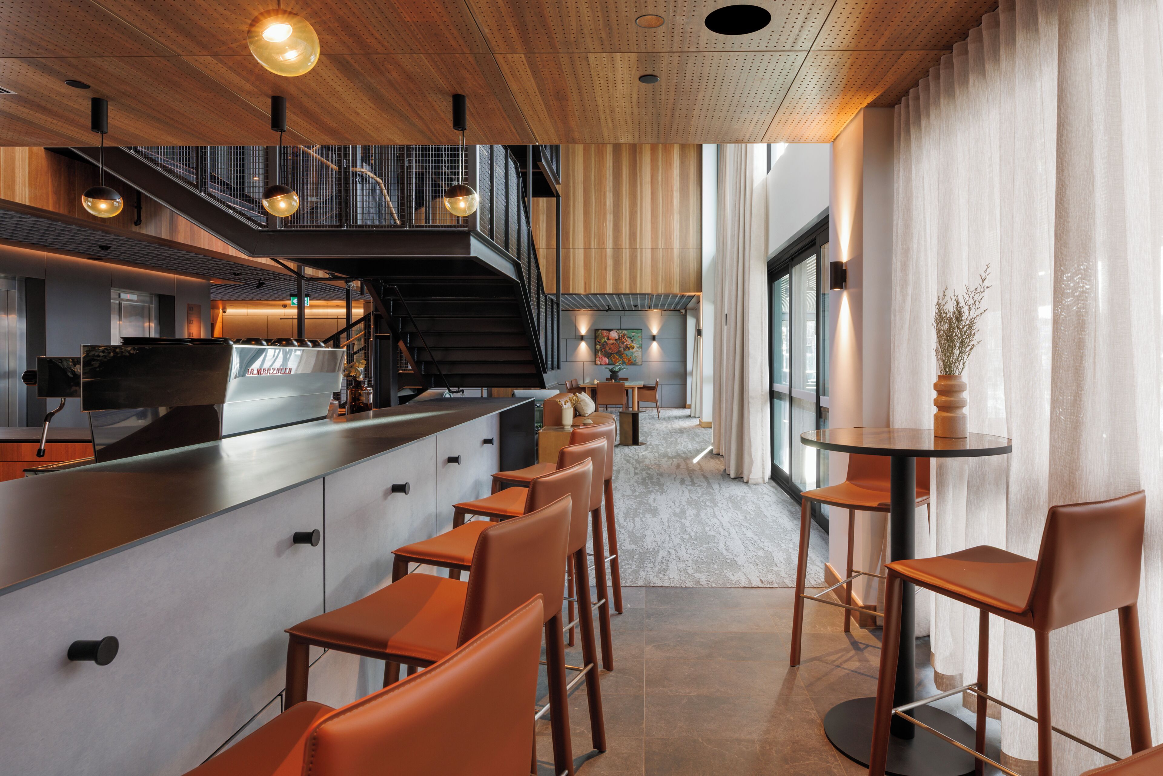 Una cocina moderna con barra, techo de madera y una escalera que lleva a un nivel superior.