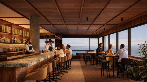 A modern bar area with a long counter, bar stools, and a view of the ocean.