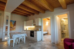 A compact kitchen with white cabinets, a dining table with chairs, and a visible oven. - Baroque - Cozy Apartment for 4 Guests | Ideal for Couples and Families (Giarratana)
