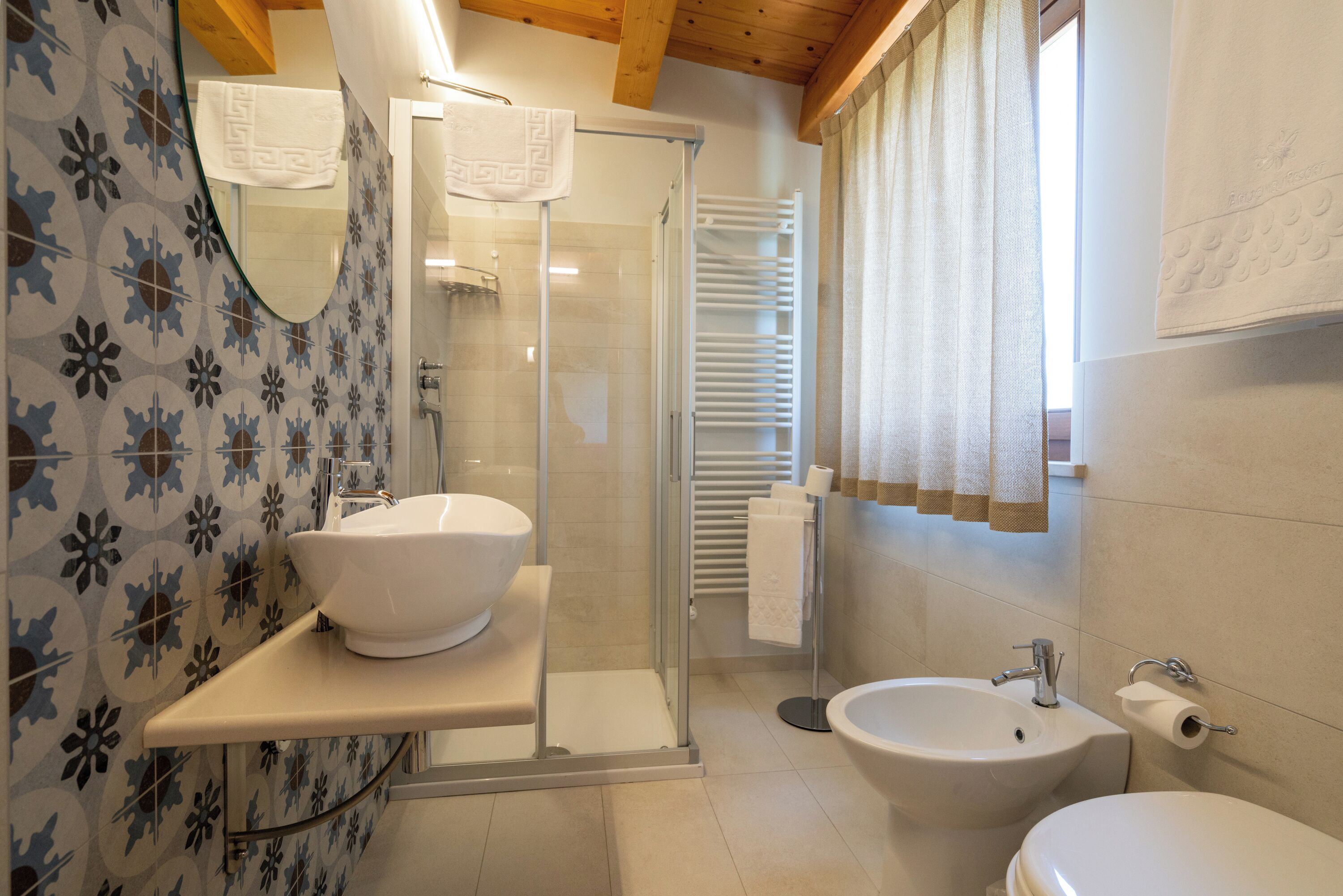 A bathroom with a glass-enclosed shower, a white sink, and a bidet.