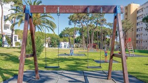 Un parco con altalene, un'area giochi e un edificio sullo sfondo.