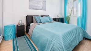 Una camera da letto con un letto, comodini, un tavolino da notte, una finestra con tende, un'opera d'arte appesa al muro e un tappeto.