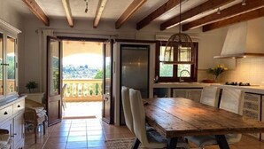 A kitchen with a wooden table, chairs, and a view to the outside. - NEW Charming country estate with swimming pool in the middle of nature (Selva)