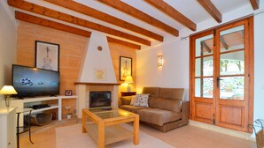 A living room with a TV, fireplace, sofa, and wooden beams. - NEW Charming country estate with swimming pool in the middle of nature (Selva)