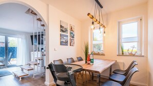 Ein Essbereich mit Holztisch und Stühlen, einer Treppe und Kunstwerken an den Wänden.
